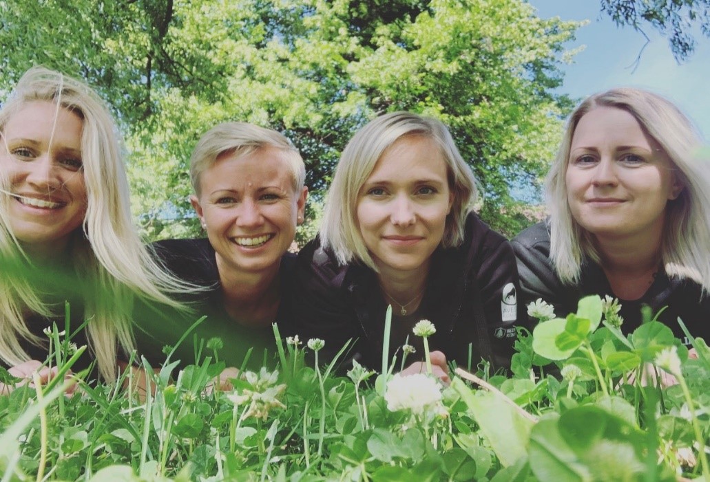 hälsoteamet ligger på gräset och ler mot kameran