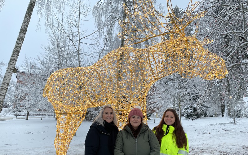 Sofie Jutner, näringslivschef, Blerta Krenzi, kommunstyrelsens ordförande och Anna Ohlén, driftingenjör står framför den stora upplysta älgen. Foto: Stina Lundkvist, Avesta kommun