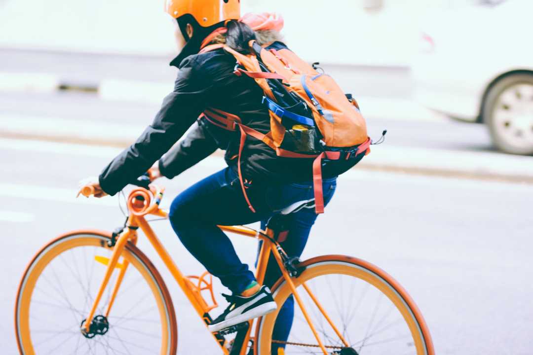 barn med cykelhjälm cyklar på en orange cykel