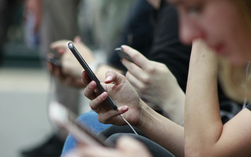 Personer som sitter och scrollar på sina mobiltelefoner.