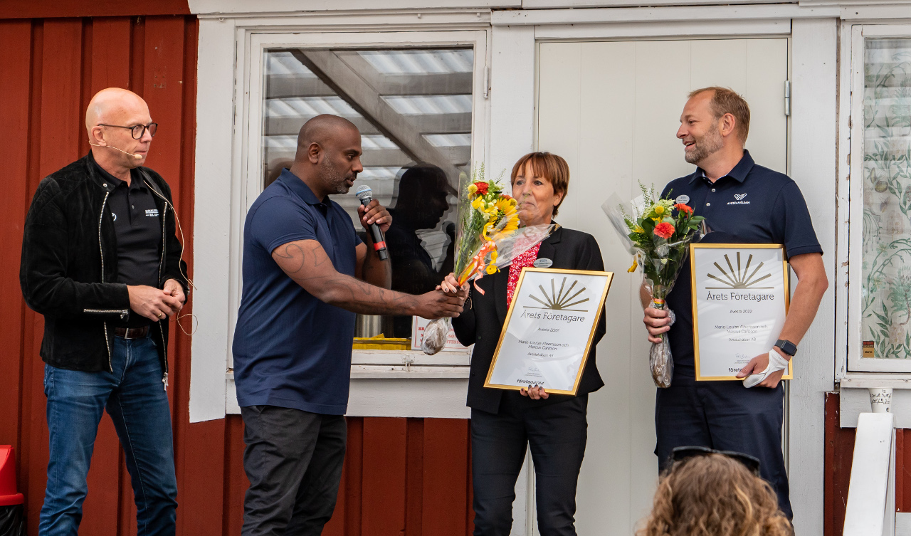 Två bpersoner överlämnar diplom och blommor till två andra personer