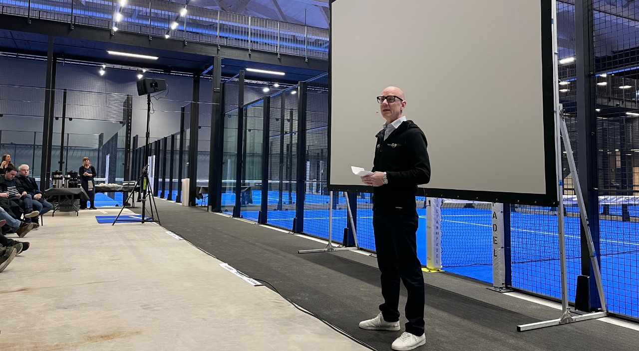 en man står i en padelhall och pratar