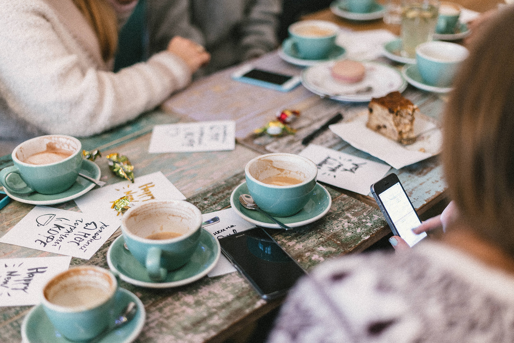 Händer vid ett fikabord med kaffekoppar och post-it lappar