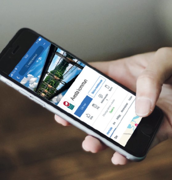 En hand som håller i en mobiltelefon med Facebook på displayen