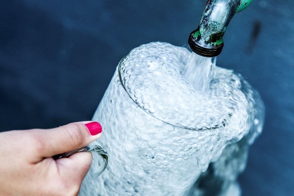Glas fylls med vatten från en kran.
