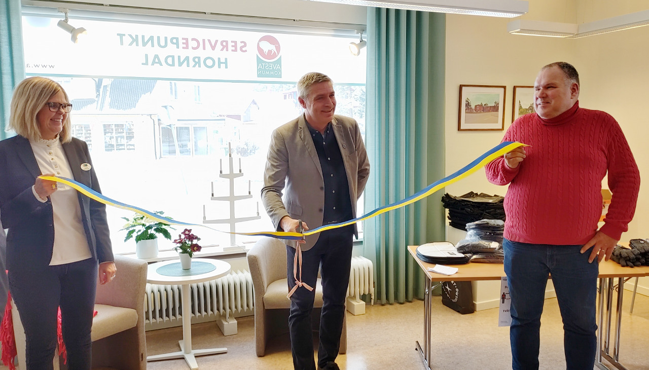 Kommunalrådet står med en sax i färd med att klippa ett band som två personer håller i
