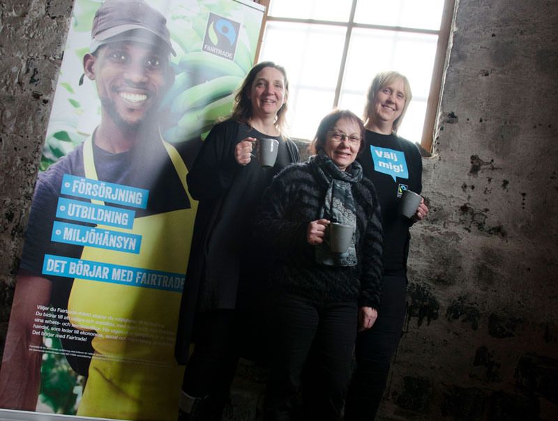 Mirjam Nykvist, hållbarhetsstrateg, Lena Jonsson, Verket, och Sussie Berger, ordförande i styrgruppen för Avesta Fairtrade City ståendes med kaffekoppar vid en Fairtrade-rullvepa i Verkets lokaler i Avesta.